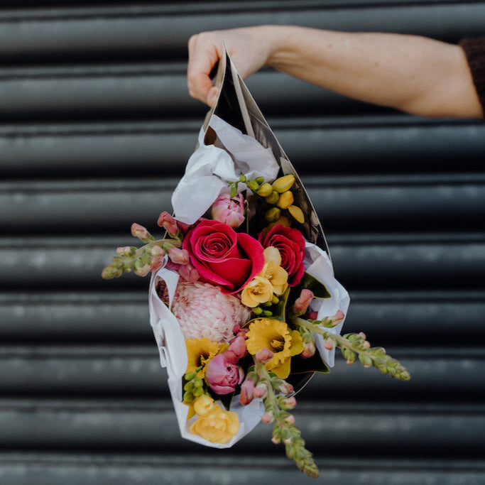 Person holding a colorful bouquet of flowers against a metallic background