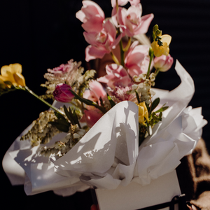 Bouquet of flowers wrapped in white paper against a dark background
