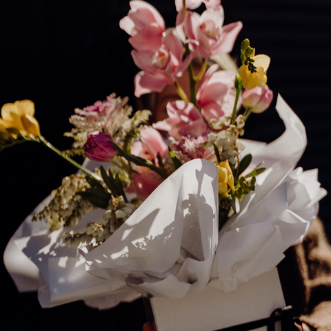 Bouquet of flowers wrapped in white paper against a dark background